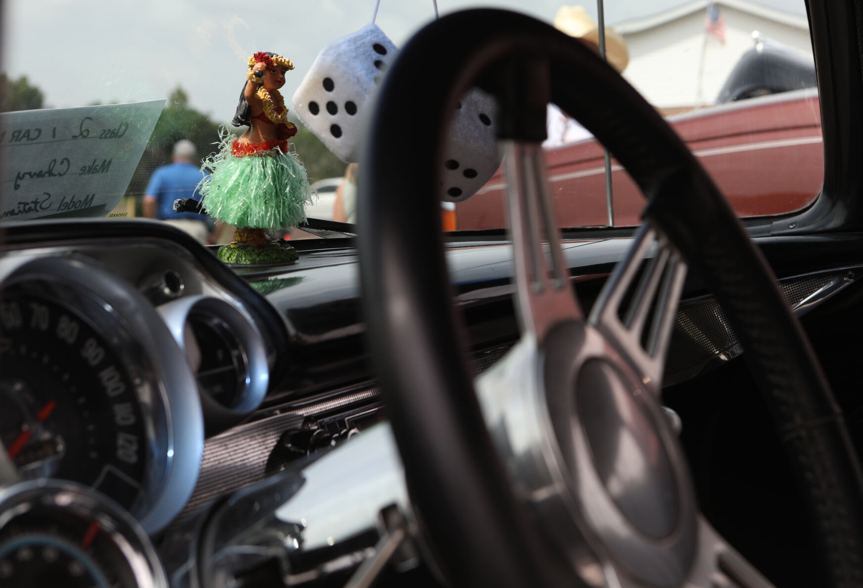 A hula dancer figurine sits on a car dashboard